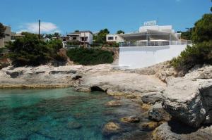un cuerpo de agua con una casa y algunas rocas en Hotel 3 Adelfia, en Agia Marina Aegina
