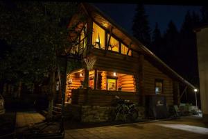 a log cabin at night with a bike parked outside at Cabana Jasmin in Băile Chirui