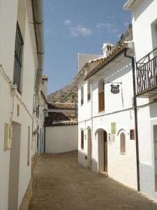 Une allée entre deux bâtiments blancs avec des montagnes en arrière-plan dans l'établissement Villa del Municipal, à Villaluenga del Rosario