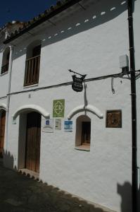 un bâtiment blanc avec des fenêtres et un panneau sur celui-ci dans l'établissement Villa del Municipal, à Villaluenga del Rosario