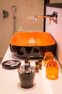 an orange sink on a bathroom counter with cosmetics at TheJoy City Suites in Chania