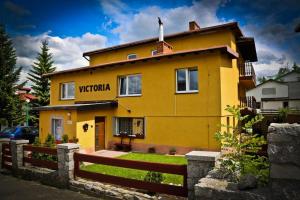 a yellow house with a fence in front of it at Willa Victoria in Szklarska Poręba