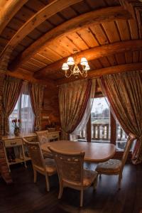 a dining room with a table and chairs and windows at Chudodiyevo Park- Hotel in Vyshpolʼ