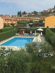 a swimming pool with chairs and umbrellas in a yard at Hotel Andreis in Cavaion Veronese