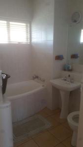 a white bathroom with a tub and a sink at Stella Maris Apartment 132 in Amanzimtoti