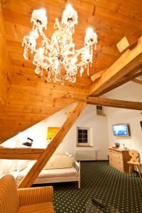 a bedroom with a wooden ceiling with a chandelier at Hotel Posta in Sedrun