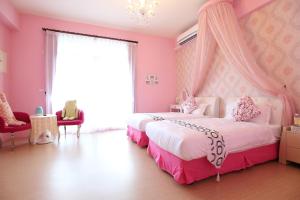 a pink bedroom with two beds and a chandelier at Aunt's Bed and Breakfast in Taitung City