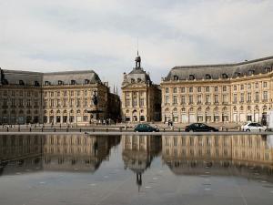 una città con due grandi edifici e un riflesso nell'acqua di Appart Cozy / Quartier St Pierre a Bordeaux