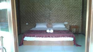 a bedroom with a bed with two slippers on it at Airas' Garden Homestay ECO Bungalows in Kuta Lombok