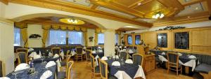 - un restaurant avec des tables et des chaises dans une salle dans l'établissement Hotel Tyrolia, à Malga Ciapela