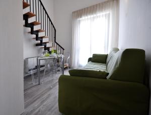a living room with a green couch and a staircase at Eden Park in Marina di Montemarciano