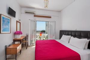 a bedroom with a large bed with a red blanket at Pension Ptolemeos in Fira