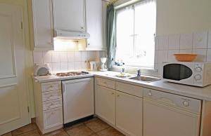 een witte keuken met een wastafel en een magnetron bij Haus-Meisennest-Wohnung-Kiebitz in Westerland