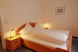 - une chambre avec un lit doté de draps et d'oreillers blancs dans l'établissement Haus-Meisennest-Wohnung-Kiebitz, à Westerland