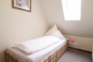 a small bed in a room with a window at Haus-Meisennest-Wohnung-Eule in Westerland (Sylt)