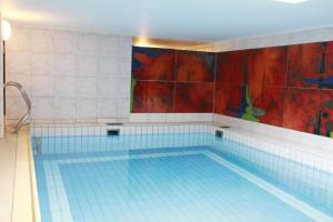 a large swimming pool with blue tiles on the wall at Haus-Meisennest-Wohnung-Eule in Westerland +1 photo