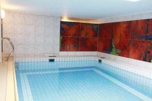 - une grande piscine avec des carreaux bleus sur le mur dans l'établissement Haus-Meisennest-Wohnung-Amsel, à Westerland