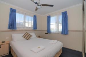 a bedroom with a large white bed with blue curtains at Kendalls Beach Holiday Park in Kiama