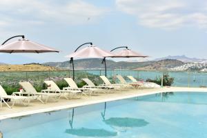 a group of chairs and umbrellas next to a swimming pool at Degirmenburnu Residence in Bodrum City