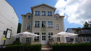 zwei weiße Regenschirme vor einem Gebäude in der Unterkunft Haus Alexander in Heringsdorf