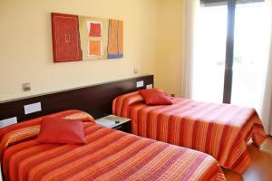 um quarto de hotel com duas camas com lençóis laranja em Apartahotel Ribera em Arroyo de la Encomienda