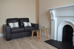 a living room with a black leather couch and a fireplace at Blessings Studio Apartments in Cootehill