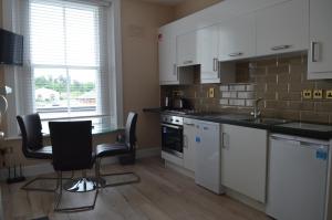 a kitchen with white cabinets and a table and chairs at Blessings Studio Apartments in Cootehill