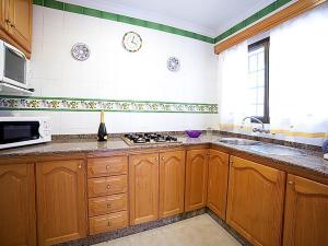 cocina con armarios de madera, fregadero y microondas en Villa Caleta 0901, en Calpe