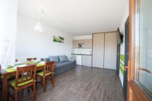 a kitchen and living room with a table and a couch at Flaming - domki letniskowe in Rowy