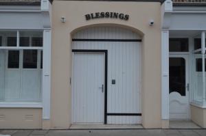 un bâtiment blanc avec une porte de garage avec les mots bénis dans l'établissement Blessings Studio Apartments, à Cootehill