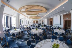a banquet hall with white tables and chairs and a chandelier at Makedonia Palace in Thessaloniki
