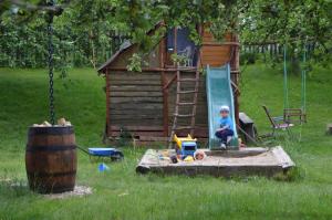 un niño pequeño sentado en un columpio frente a un parque infantil en Ubytování Na Vejminku en Rtyně v Podkrkonoší
