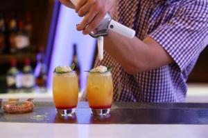 a man is preparing two cocktails on a counter at Elite City Resort in Kalamata