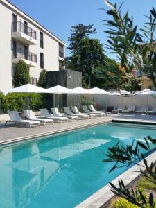 サントロペにあるExclusive Resort Apartment Saint Tropezの建物の隣にスイミングプール(椅子、パラソル付)