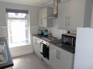 a kitchen with white cabinets and a stove top oven at Jeffersons Hotel & Serviced Apartments - The Steel Works in Barrow in Furness