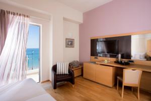 a bedroom with a bed and a desk with a television at Elite City Resort in Kalamata