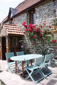 une table et des chaises devant un bâtiment avec des roses dans l'établissement Normandy Nature Paradise, à Vire