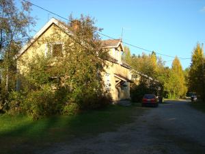 una vecchia casa con un'auto parcheggiata sul ciglio di una strada di Gran Hotellihuoneistot 1 a Suolahti
