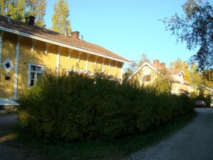 une maison jaune avec une grande brousse devant elle dans l'établissement Gran Hotellihuoneistot 1, à Suolahti