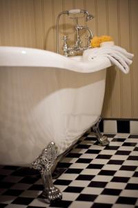 a bath tub with a sink on a black and white floor at Gran Hotellihuoneistot 1 in Suolahti
