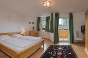 ゼーフェルト・イン・チロルにあるHaus Elisengrundのベッドルーム(ベッド1台、テレビ、緑のカーテン付)