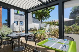 two tables and chairs on a patio with a view of a pool at Campanile Carcassonne Est - La Cité in Carcassonne