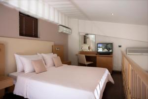 a hotel room with a white bed and a television at Elite City Resort in Kalamata