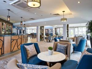 a lobby with blue chairs and tables and a bar at Staverton Park Hotel & Golf Club in Daventry