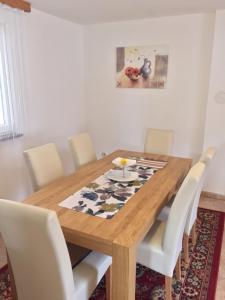 uma mesa de jantar com cadeiras brancas e uma mesa de madeira em Lavanda Haus em Vodnjan