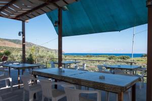 een groep tafels en stoelen met uitzicht op de oceaan bij Blue Bay Hotel in Charamida