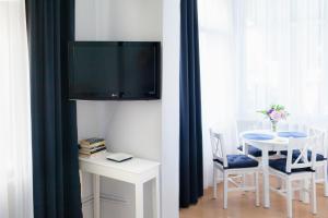 a living room with a table and a tv on a wall at Pod Cisami Apartments in Międzyzdroje