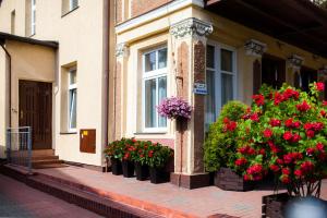 a row of flower pots on the side of a building with flowers at Pod Cisami Apartments in Międzyzdroje