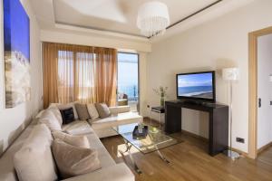 a living room with a white couch and a television at Elite City Resort in Kalamata