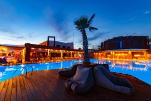 uma piscina com uma palmeira ao lado de um edifício em Elite City Resort em Kalamata